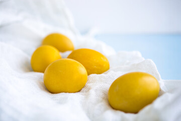 Yellow Easter eggs on a white napkin on a light background, toned, soft selective focus. Festive background with Easter symbols