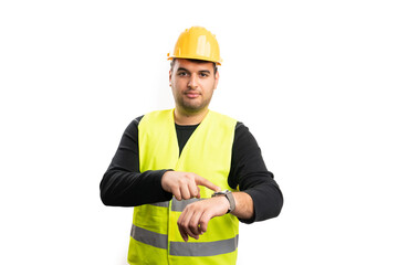 Builder with serious expression pointing at watch timekeeping