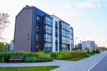 Obraz premium Modern complex building. Street with road and sidewalk. New apartment buildings in green enviroment. Landscaping for urban spaces. Building exterior, house block. Condominium in residential area.
