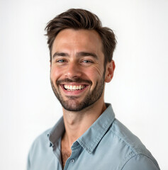 Obraz premium Portrait of a handsome young man smiling and wearing a light blue shirt with the top button undone, isolated over a white background