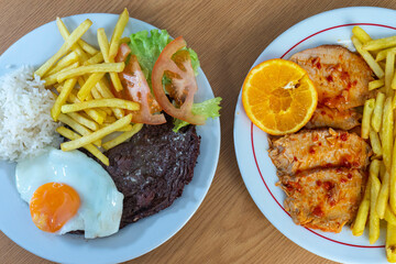 Traditional Portuguese meal with roasted pork loin and fries, and bitoque with a fried egg, served in a cozy restaurant setting. Authentic Portuguese cuisine at its best.