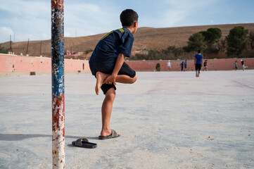 young boy in flip=floops standing in goal holds his leg because of an injury sustained during a...