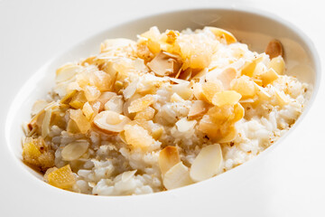 Creamy rice pudding topped with slivers of almond and sweet caramelized pieces. Perfect for dessert lovers, this dish showcases a delicious blend of textures and flavors. Ideal for food photography.