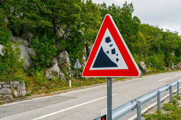 rockfall warning sign on the background of the crumbling hillside, stone fall warning sign