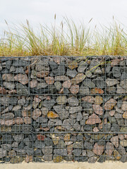 Gabion fence wall from steel mesh filled with granite stones, modern seaside environmental object
