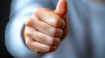 Close-up of a human hand giving a thumbs-up gesture against a dark background, symbolizing positivity