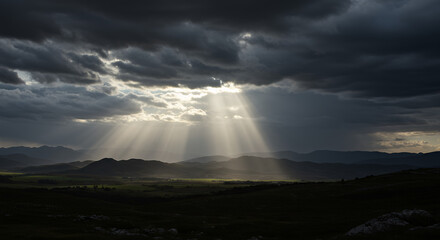 Dramatic Sunbeams Breaking Through Dark Storm Clouds Over Rolling Hills