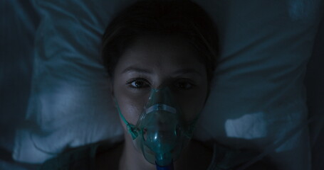 Female patient wearing oxygen mask looking directly at camera.