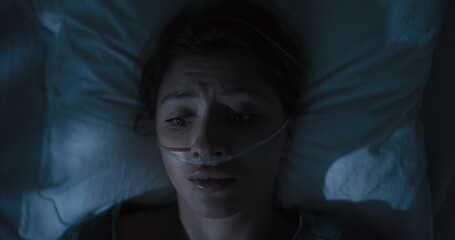 Terrified woman in hospital bed has a panic attack.