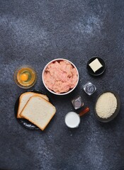 Prepared ingredients for cooking chicken cutlets on a black concrete background. Ingredient layout. Step-by-step recipes.