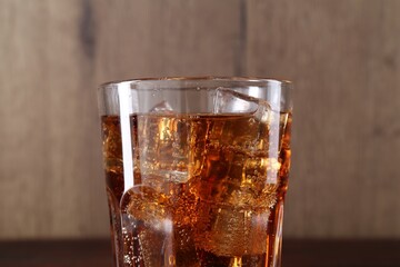 Sweet soda water with ice cubes in glass on blurred background, closeup