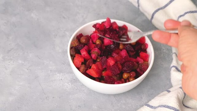 Hand with a fork taking vinaigrette beetroot salad on neutral background. High quality 4k footage