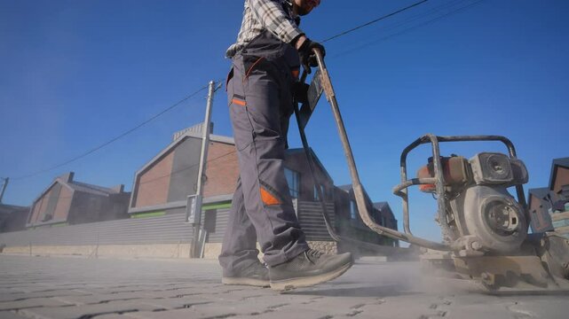 Worker Operating Vibratory Plate Compactor on Pavement