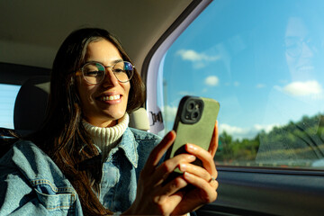 A young woman scrolling through her phone and responding to messages during a car ride