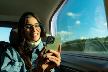 A woman in the car’s passenger seat, checking social media updates on her phone