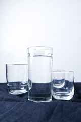 Glass of water with white background. Close-up glasses with copy space. Concept of drinking, clean, eating healthy, and liquid. The glass has a pure water placed on black fabric with a white wall