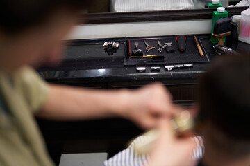 Barber carefully styling hair with a variety of tools on the counter