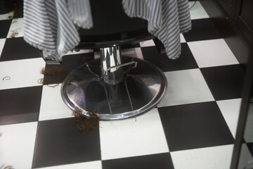 Hair remnants on the floor beneath a salon chair in a busy barber shop