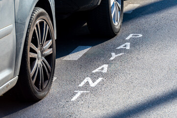 Marquage au sol "PAYANT" écrit en français indiquant une place de stationnement automobile payante dans une rue de Paris, France. Concepts de places de parking et de prix du stationnement en ville