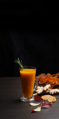 Sea buckthorn tea in a tall transparent mug on a black background
