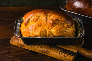 Sweet brioche bun in a bread baking pan, on a dark background. Delicious homemade pastries