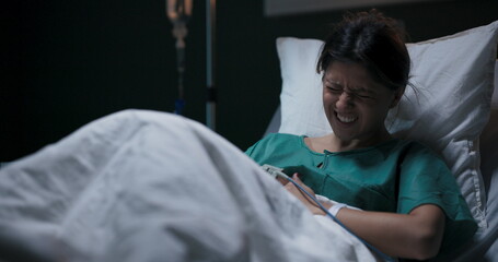 Female patient in hospital ward lying in bed suffering from gastritis.