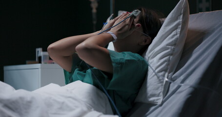 Exhausted female patient in hospital ward cries because of stomachache.