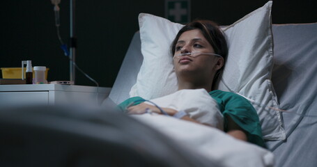 Exhausted young female patient in hospital ward with tube in nose.