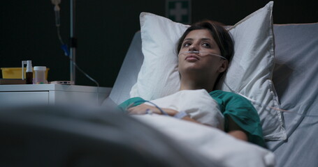 Exhausted young female patient in hospital ward with tube in nose.