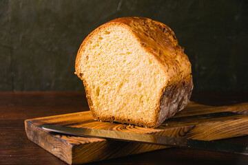 Sweet brioche bun cut on a wooden cutting board and bread knife. Delicious home baked goods