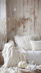 rustic interior with soft knitted pillows and blankets in white tones, dried plants, and minimal autumn decor