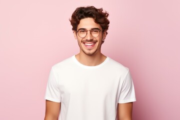Obraz premium Portrait of a joyful young man wearing glasses and a white t shirt, smiling broadly against a pink backdrop