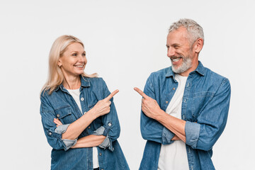 Mature happy couple two friends family man woman wears casual clothes point index finger on each other area between them together isolated on white color background studio portrait