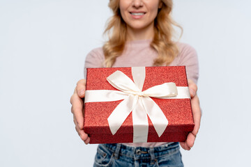 Close up of Caucasian woman holding giving red present box gift with white ribbon bow while...