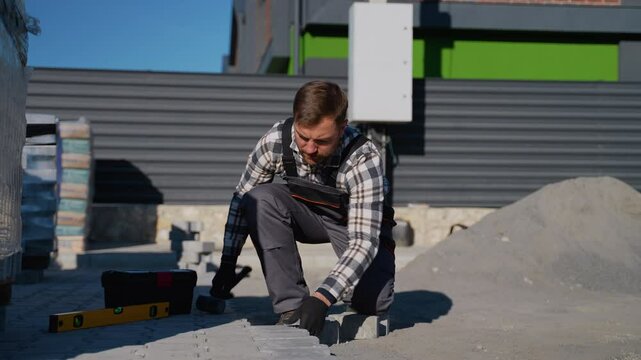 Construction worker laying paving stones outdoors