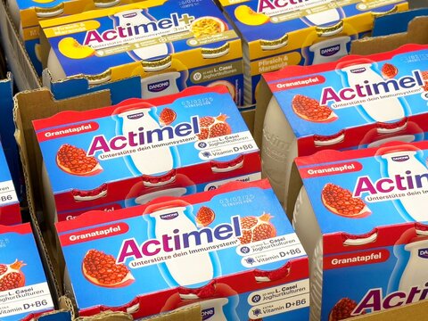 Assorted actimel yogurt packs with pomegranate and peach flavors in cardboard cartons