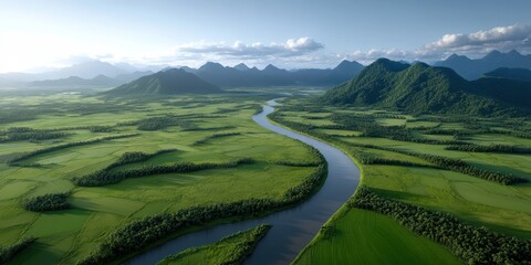 Fototapeta premium A serene landscape with a meandering river cutting through vast green fields under a tranquil blue sky, flanked by distant mountains.