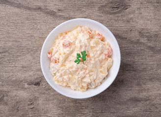 Russian salad or mayonnaise salad in a plate over wooden table