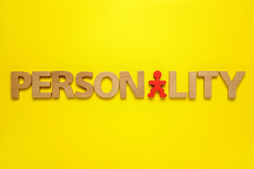 Word Personality made of wooden letters and red human figure on yellow background, top view