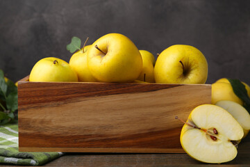Ripe yellow apples in wooden crate on table