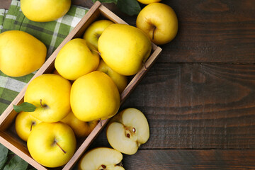 Ripe yellow apples in crate on wooden table, top view. Space for text
