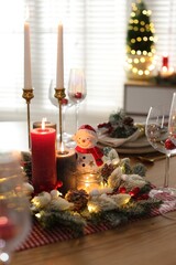 Christmas place setting with festive decor on wooden table in room