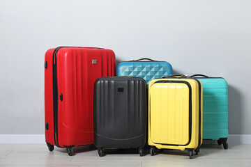 Many colorful suitcases on floor near light wall