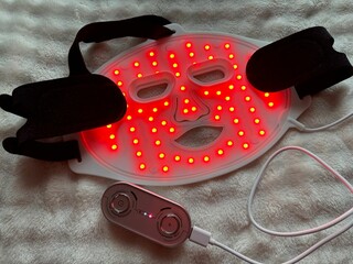 Led light therapy face mask on soft fabric, above view. Beauty treatment