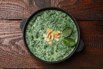 Delicious spinach sauce with peanuts on wooden table, top view
