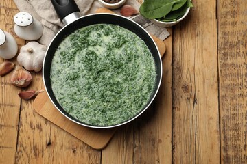 Delicious spinach sauce served on wooden table, flat lay