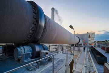 Naklejka premium Rotating furnace for limestone roasting at plant in evening