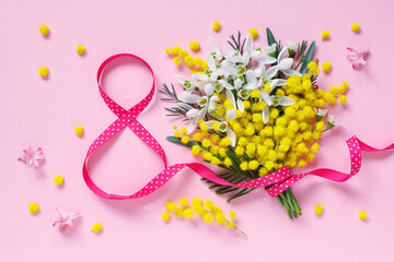 Number eight from a ribbon and a bouquet of snowdrops with mimosa on a pink background. Postcard for International Women's Day, March 8