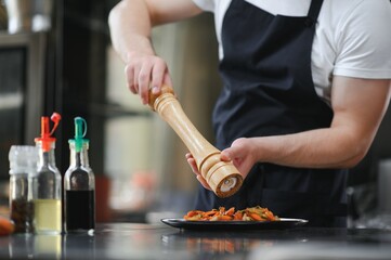 Chef cook in uniform cooking in the big cooker at the restaurant kitchen