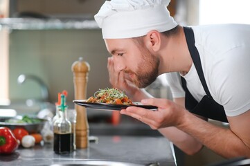 Closeup of a concentrated male chef garnishing food in the kitchen